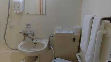 A compact bathroom with a toilet, sink, and shower.