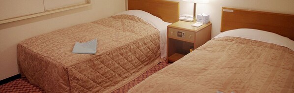 Two single beds with matching headboards, a bedside table with a lamp, and a small drawer unit.