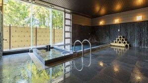 Una grande piscina al coperto con un pontile in legno e una parete in pietra.