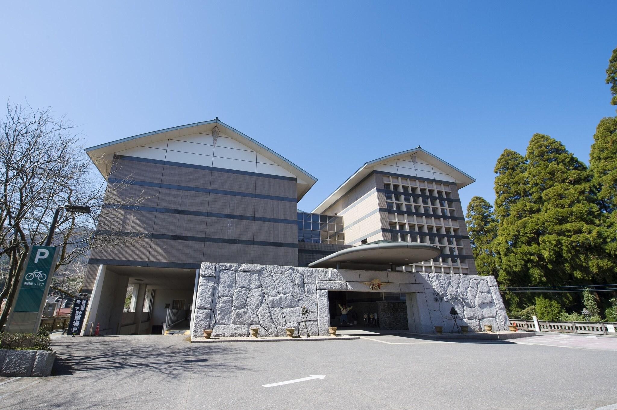 Un bâtiment moderne avec un panneau indiquant un parking, une façade en pierre et un ciel dégagé.