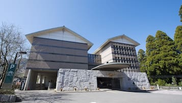 Un bâtiment moderne avec un panneau indiquant un parking, une façade en pierre et un ciel dégagé.