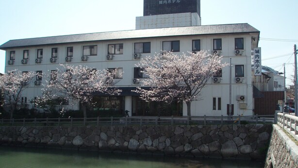 A building with multiple windows and a stone wall in front. - Jyonai Hotel (Karatsu)