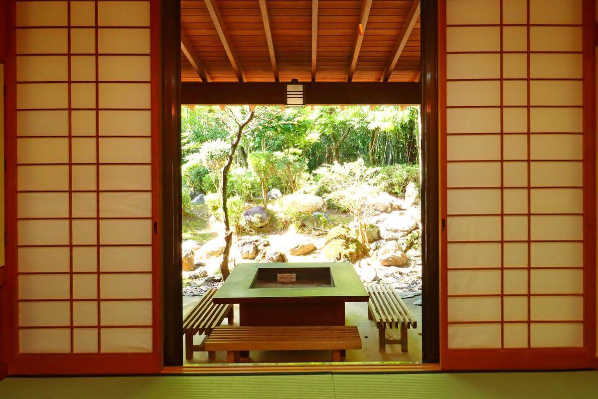 Een traditionele Japanse kamer met tatami vloerbedekking, een lage tafel en zitbanken.