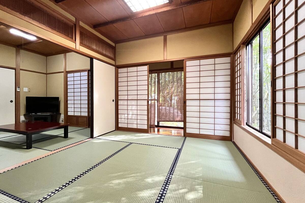 Een traditionele Japanse kamer met tatami vloerbedekking, schuifdeuren en een televisie.