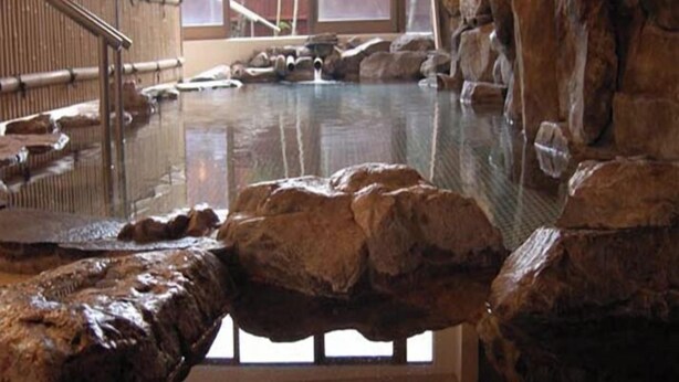 A hot spring area with stone walls and a wooden deck. - Ryokan Satsumanosato (Satsumasendai)