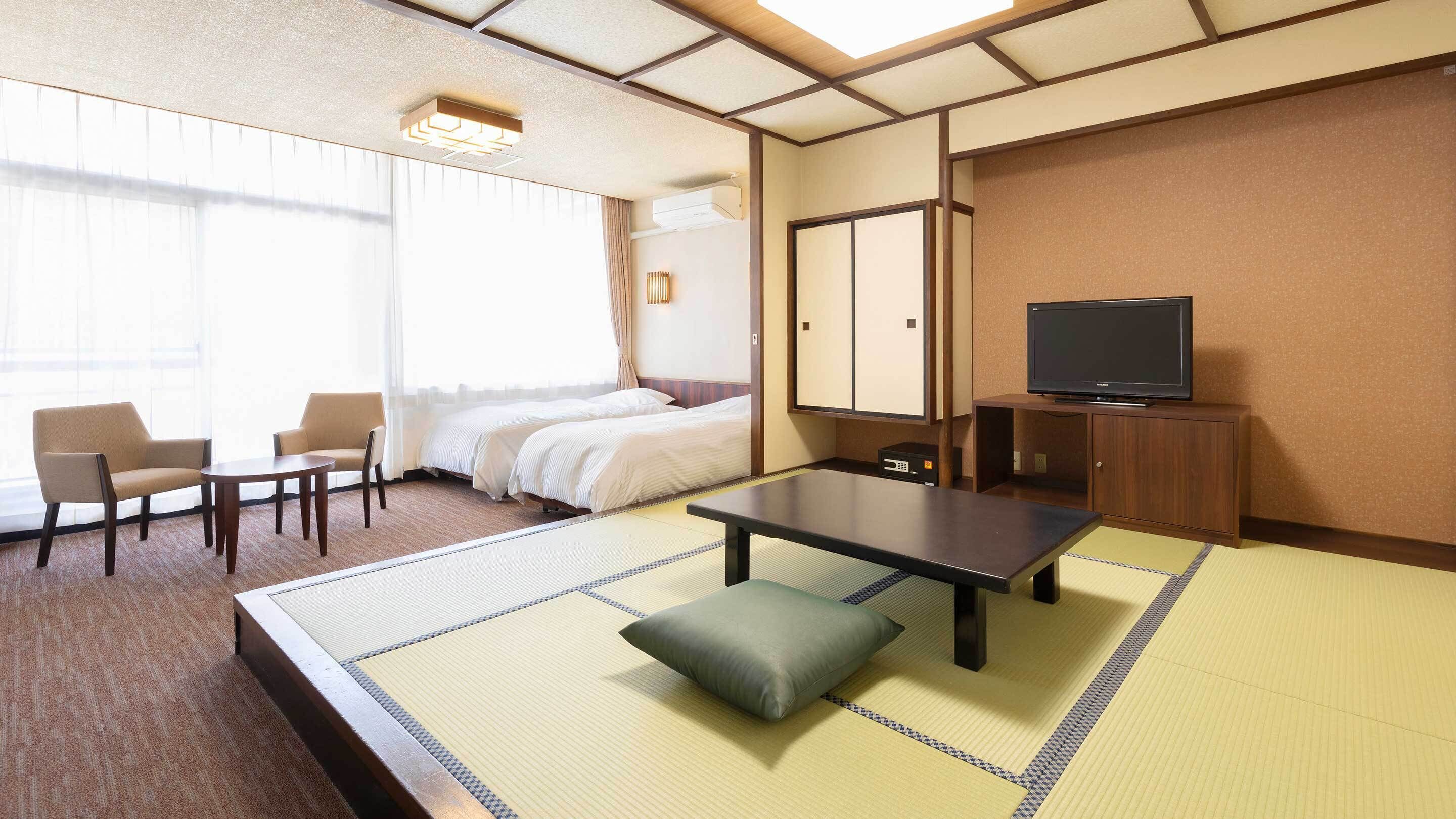 Una habitación de hotel con cama, escritorio, silla, televisión y suelo de tatami japonés tradicional.