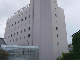 Un edificio de varios pisos con un diseño arquitectónico moderno, que presenta una serie de ventanas y balcones.