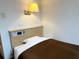 Una habitación de hotel con una cama, una lámpara de pared y un panel de control.