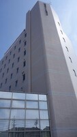 Un edificio de gran altura con un diseño arquitectónico moderno, que destaca por su sección de esquina y numerosos ventanales.