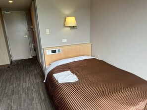 A hotel room with a bed, a bedside table, a lamp, and a wall-mounted control panel. - Nakamura Prince Hotel (Shimanto)