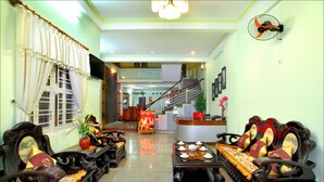 A traditional-style living room with a sofa set, a table with teapots, and a staircase leading to an upper level. - Hoi An Life Homestay (Da Nang)