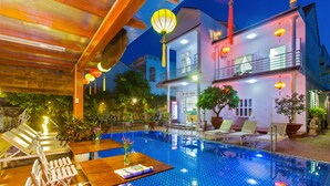 A hotel with a swimming pool, lounge chairs, and a dining area. - Hoi An Life Homestay (Da Nang)