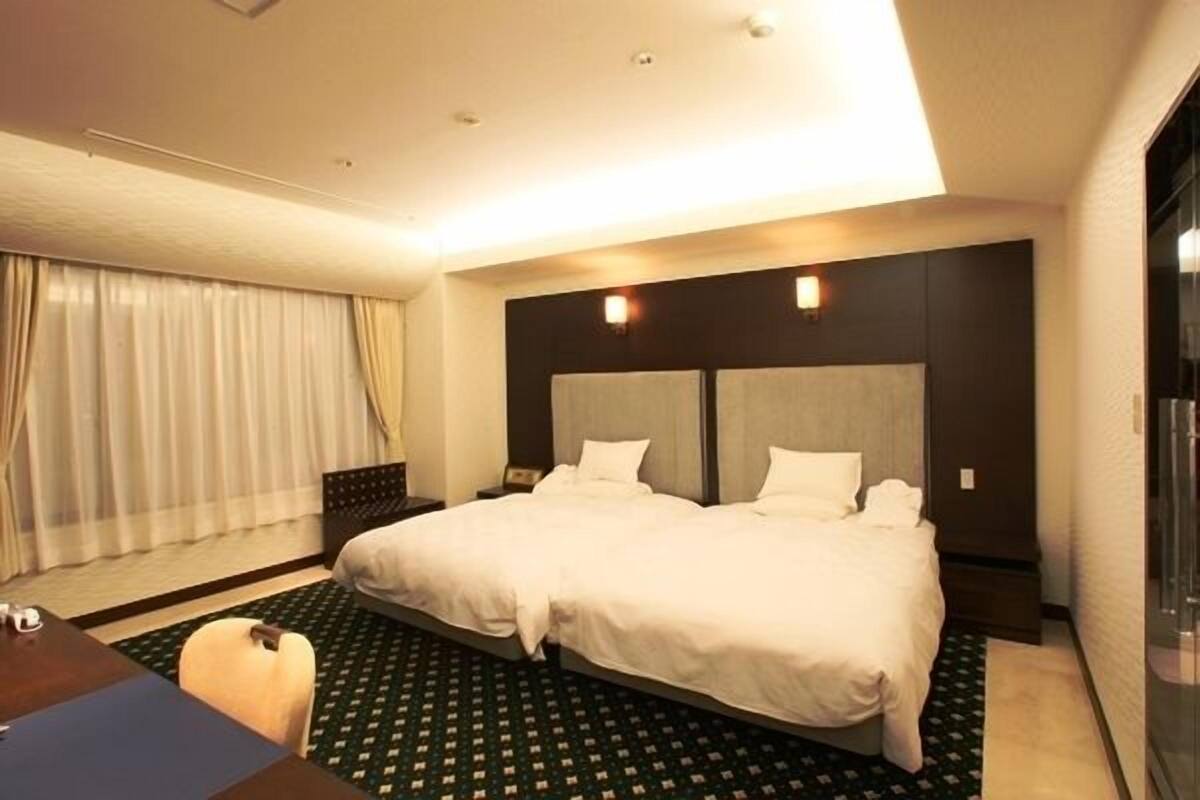 A hotel room with a large bed, a desk, and a chair.