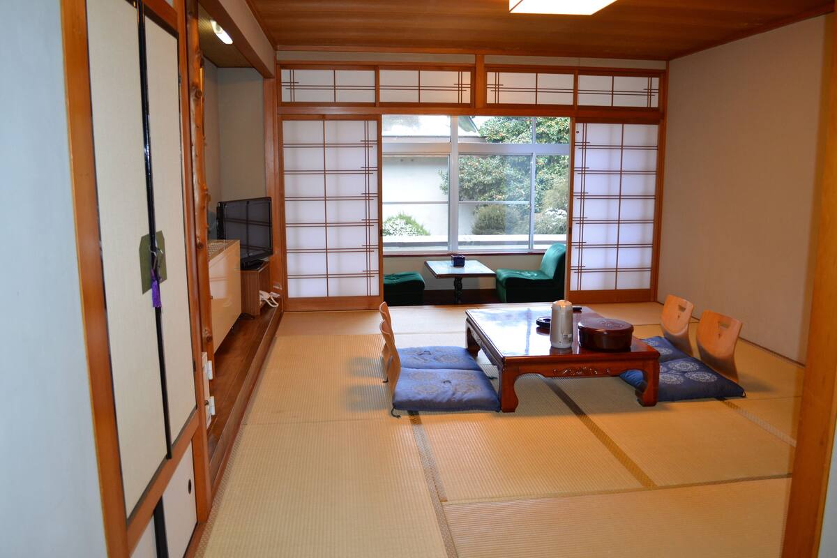 A traditional Japanese room with tatami flooring, a low table with cushions, and sliding doors.