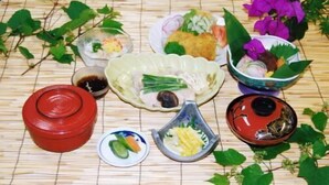 Una mesa con diferentes platos, un recipiente rojo y un tazón pequeño con tapa.