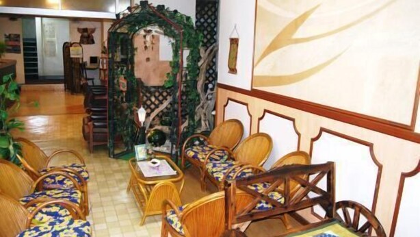 Una habitación con un banco de madera, una pequeña mesa y un arco decorativo.