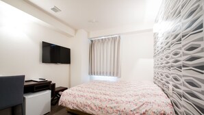 Une chambre d’hôtel avec un lit, un bureau avec un ordinateur, une télévision et une fenêtre avec des rideaux.