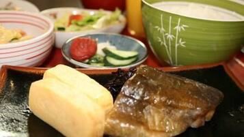 A meal with a piece of meat, a bowl of soup, and a plate with a small dish of salad.
