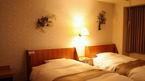 A hotel room with two beds, a nightstand, a lamp, and wall-mounted decor. - Ibaraki Central Hotel (Ibaraki)