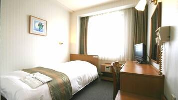 Ein Hotelzimmer mit einem Bett, einem Schreibtisch, einem Fernseher und einem Fenster mit Vorhängen.