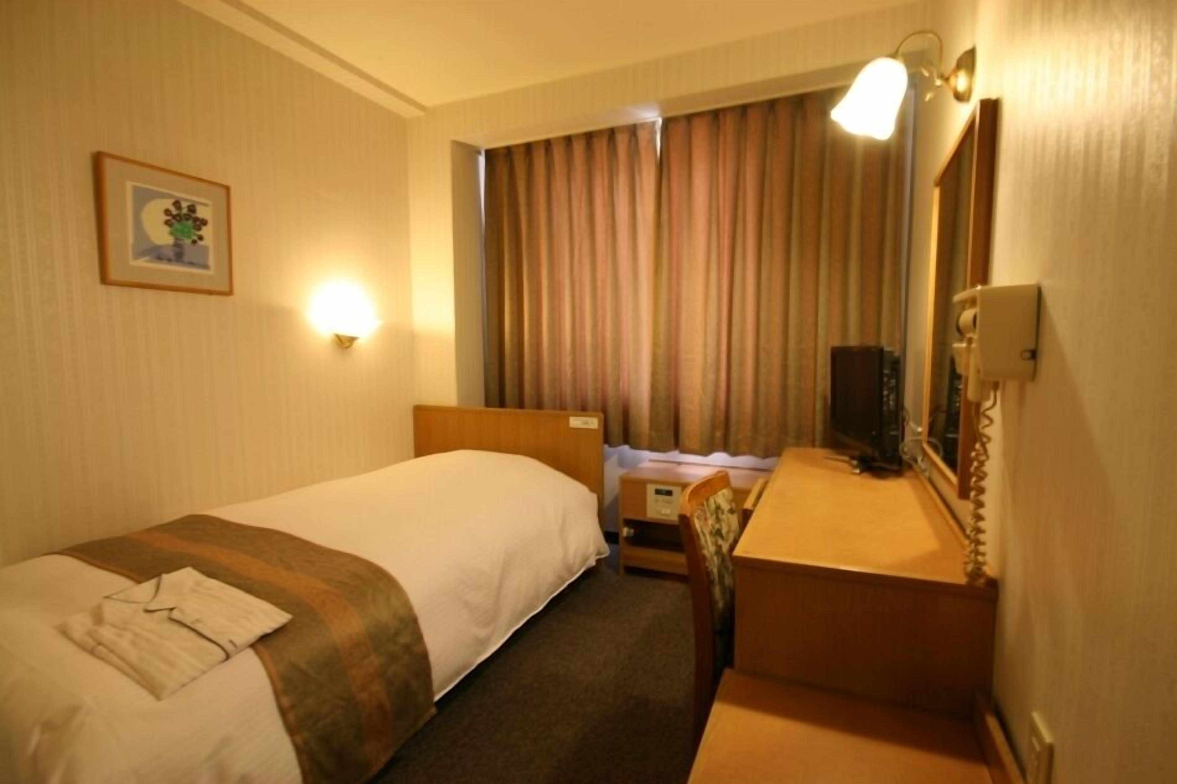 A hotel room with two beds, a desk, a chair, a television, and a picture on the wall.