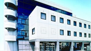 A modern hotel with a white facade, multiple windows, and a curved balcony structure. - Ibaraki Central Hotel (Ibaraki)