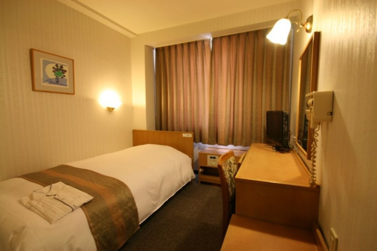 A hotel room with two beds, a desk, a chair, a television, and a picture on the wall.