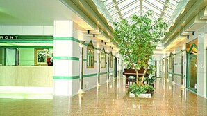 A hotel lobby with a reception desk labeled 'FRONT,' a central plant, and a glass ceiling. - Ibaraki Central Hotel (Ibaraki)