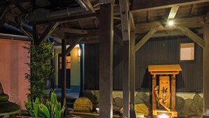 A rustic interior with exposed wooden beams, a stone wall, and a small shrine with a statue. - Hotel Shoryuen Kaisei (Kamiamakusa)