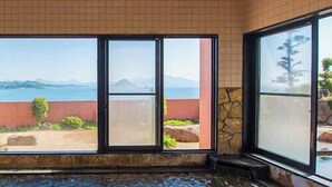 A room with large windows offering a view of the sea and mountains. - Hotel Shoryuen Kaisei (Kamiamakusa)