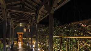 An indoor covered area with a wooden ceiling, a stone floor, and a railing with plants. - Hotel Shoryuen Kaisei (Kamiamakusa)