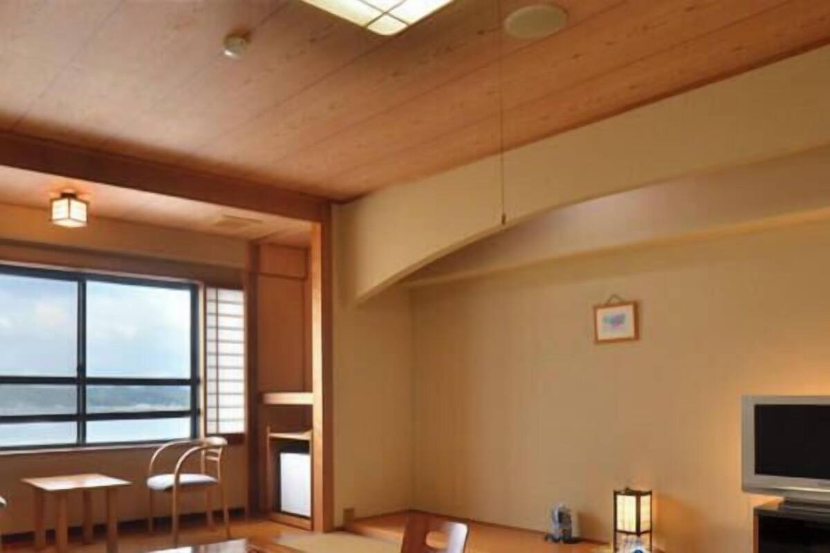 A room with a large window, wooden ceiling, and a flat-screen TV.