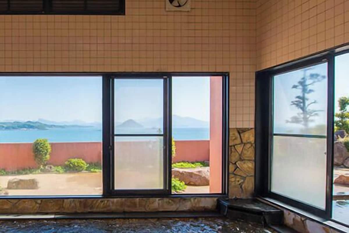 A room with large windows offering a view of the sea and mountains.