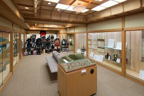 A traditional Japanese room with tatami flooring, a display case with historical artifacts, and a collection of kimonos. - Akayu Onsen Gotenmori (Nanyo)