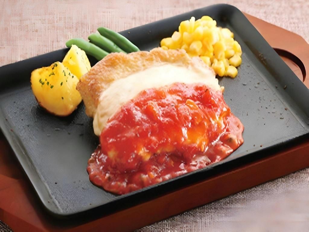 A meal with a breaded cutlet, tomato sauce, corn, green beans, and boiled potatoes on a black plate.