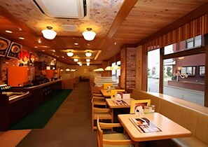 A restaurant interior with wooden tables and chairs, a counter with a menu, and a view of the street through large windows. - Hotel Lexton Tokunoshima Tokunoshima (Tokunoshima)