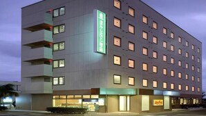 A multi-story hotel with a modern design, featuring balconies on the upper floors and a visible restaurant at the ground level.