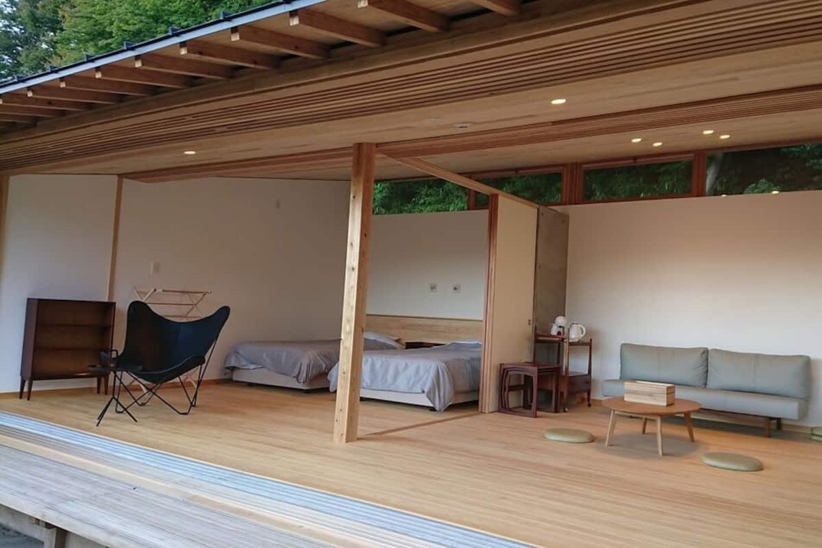 Una habitación moderna de planta abierta con suelo de madera, una cama, un sofá, una silla y una pequeña mesa.