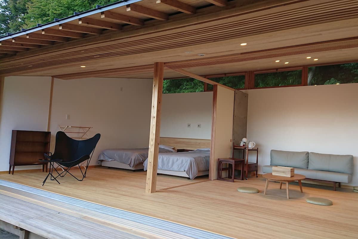 Una habitación moderna y de planta abierta con cama, sofá, sillón y una mesita.