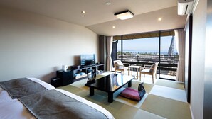 A hotel room with a bed, a desk, a chair, a TV, and a balcony with a city view. - Choubounoyado Shiori (Beppu)