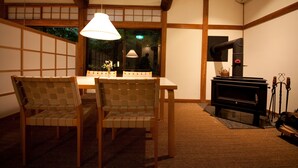 Una habitación japonesa tradicional con suelo de tatami, una mesa baja y una estufa de leña empotrada.
