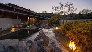 A traditional Japanese-style building with a koi pond, stone pathway, and lanterns.