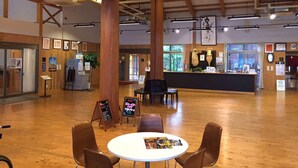 A spacious indoor area with wooden flooring, a reception desk, and several seating arrangements. - Fontana No Oka Kamo (Aira)