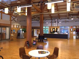 A spacious indoor area with wooden flooring, a reception desk, and several seating arrangements.