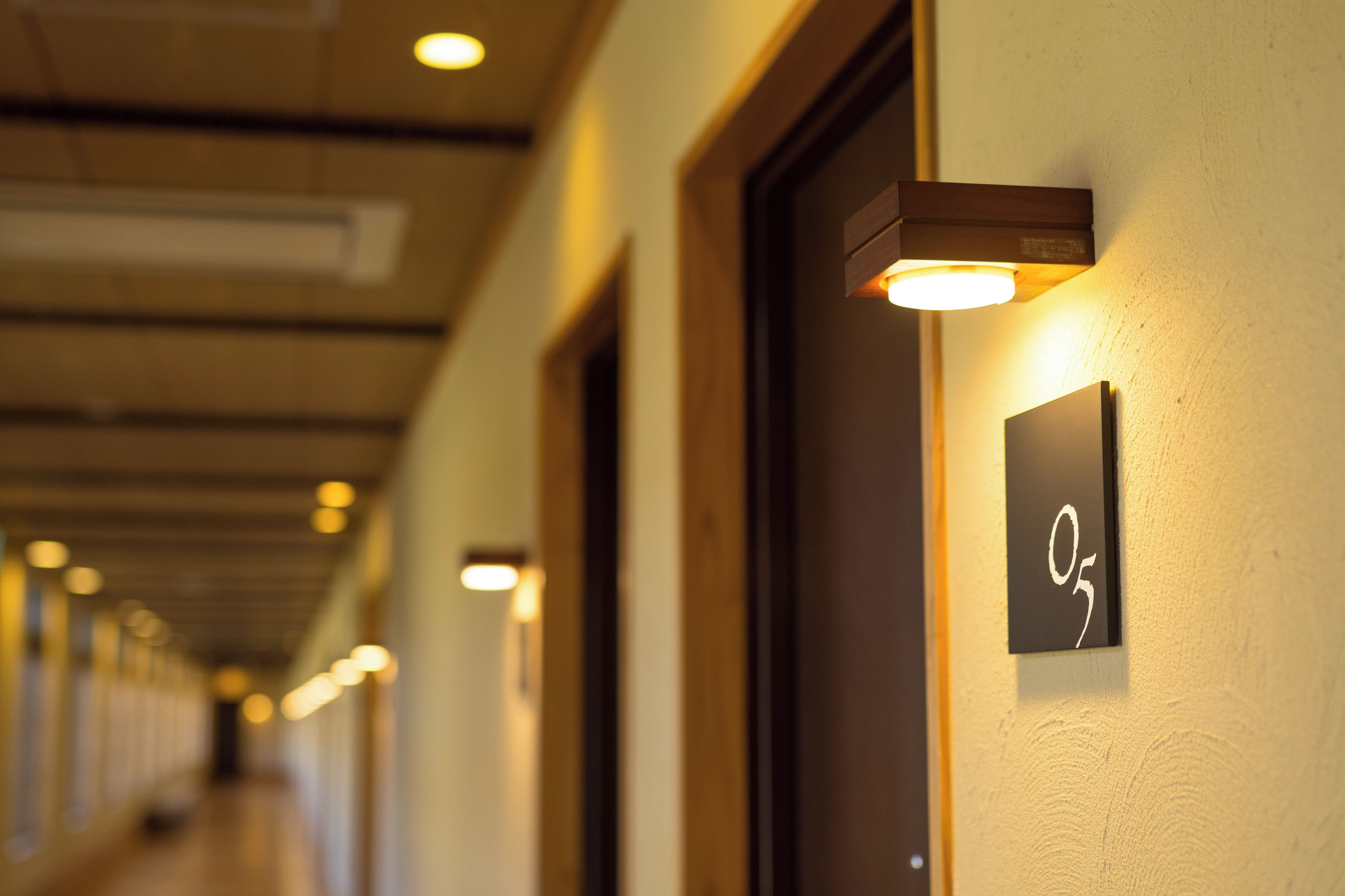 Ein Hotelgang mit Türen und beleuchteten Schildern.