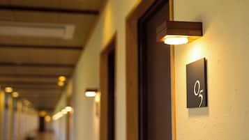 Ein Hotelgang mit Türen und beleuchteten Schildern.