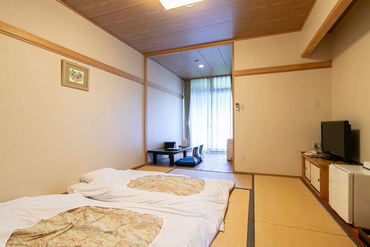 Habitación de hotel con dos camas, un escritorio, un televisor y un refrigerador pequeño.