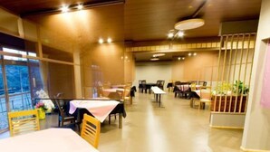 Un restaurante con mesas y sillas de madera, vistas a través de amplios ventanales y una decoración de estilo moderno.