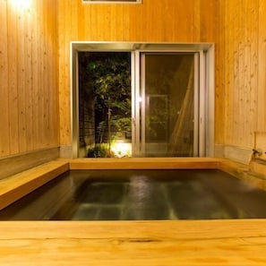 Un sauna en bois doté d’une porte en verre, d’un petit banc et d’une source de lumière placée sur le banc.