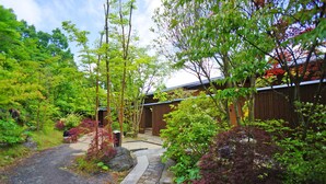 A traditional Japanese-style garden with a stone pathway leading to a wooden building.
